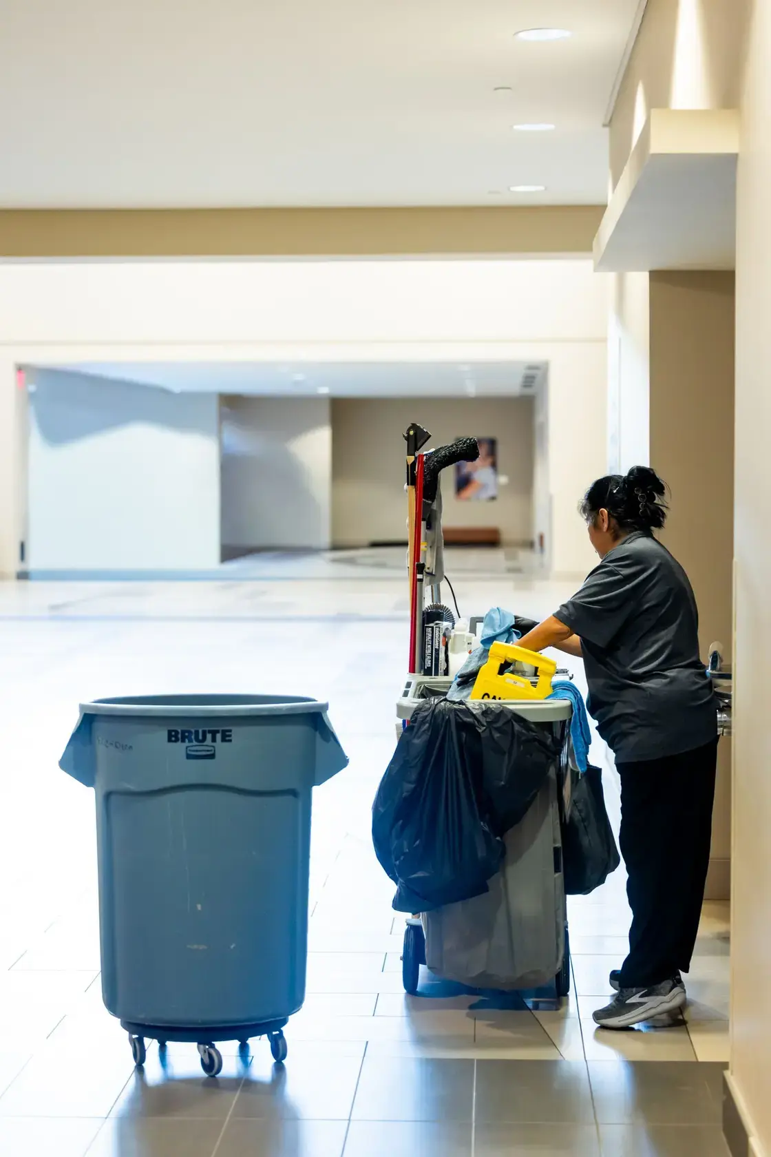 Commercial cleaner with a professional cleaning trolley in a large indoor building