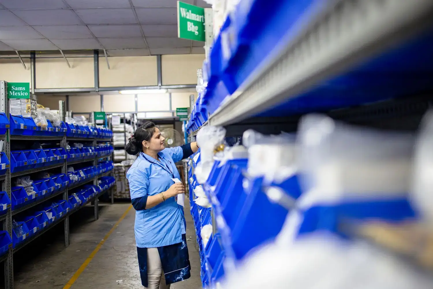 Warehouse operative in a hi-vis vest organising stock on shelving
